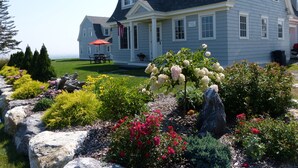 Une grande maison dotée d’un jardin bien entretenu, d’une terrasse avec mobilier d’extérieur et offrant une vue sur l’océan.