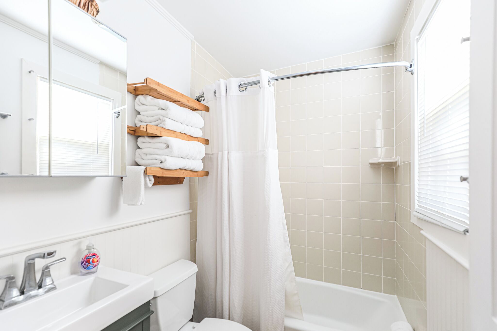 Ein Badezimmer mit Waschbecken, Toilette und Dusche. An der Waschbecken befindet sich ein Handtuchhalter mit gefalteten Handtüchern und eine Seife.