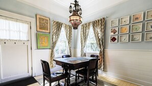 Une salle à manger avec une table en bois, quatre chaises, un lustre et des tableaux encadrés accrochés au mur.