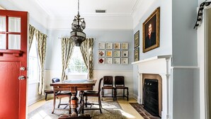 Une salle à manger avec une table en bois, des chaises, un lustre et une cheminée.