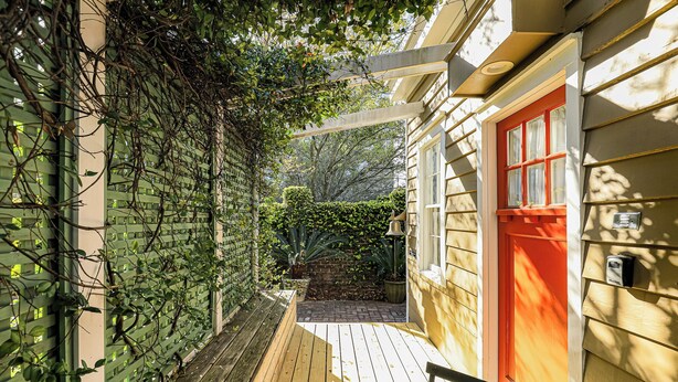 Une terrasse en bois avec un mur en treillis vert et une porte rouge.