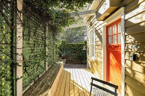 Una terraza de madera con un muro de celosía verde y una puerta roja.