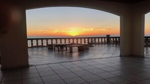 Une terrasse offrant une vue sur le coucher du soleil, avec une table et des chaises.