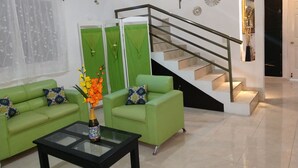 A modern living room with green sofas, a glass coffee table, and a staircase with a metal railing. - **New Listing**  Close to the Sea, 2 blocks from the Beach (Chicxulub Puerto)