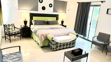A modern bedroom with a bed, two chairs, a small table, and a ceiling fan.