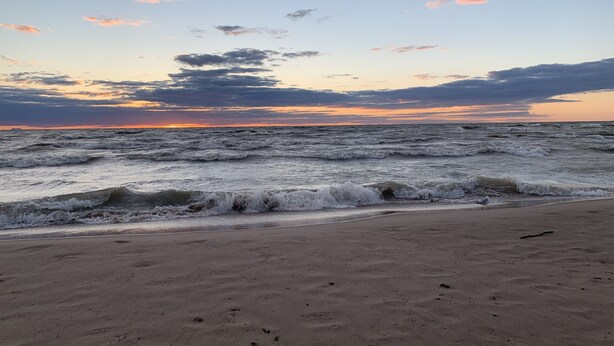 Een strand met golven en een zonsondergang.