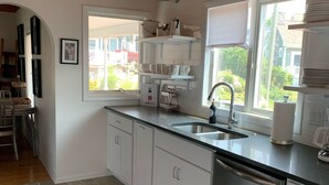 Een moderne keuken met witte kasten, een RVS vaatwasser en een raam met uitzicht.