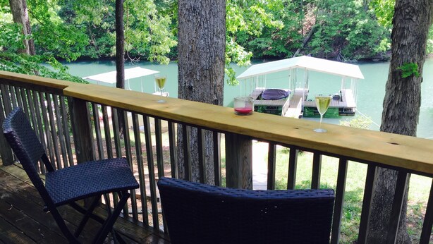 A wooden deck with two wicker chairs and a table, overlooking a lake with a covered area and lounge chairs. - Quiet cove, deep water, minutes to Clemson, pet friendly, easy path to the dock (Seneca)