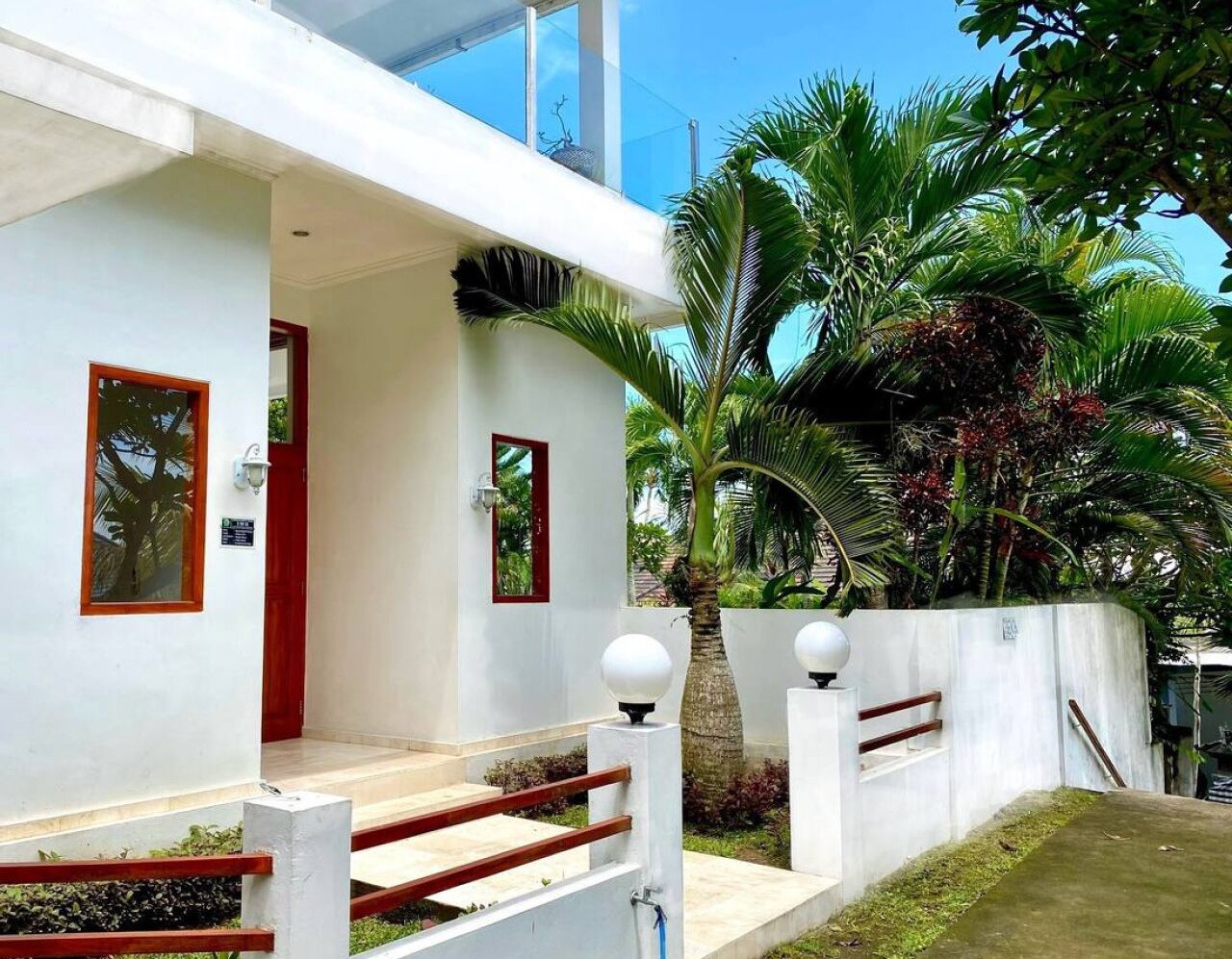 A modern building with a white exterior, red-framed windows, and a covered entrance.