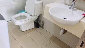 Casa de banho com sanita, lavatório e espelho sobre o lavatório.