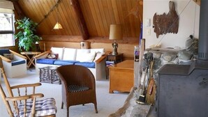 Una sala de estar acogedora con techo de madera, chimenea, sillón mecededor, sofá y una mesa de centro.