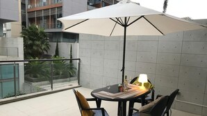 Um pátio com mesa, cadeiras, um guarda-sol e uma luminária.
