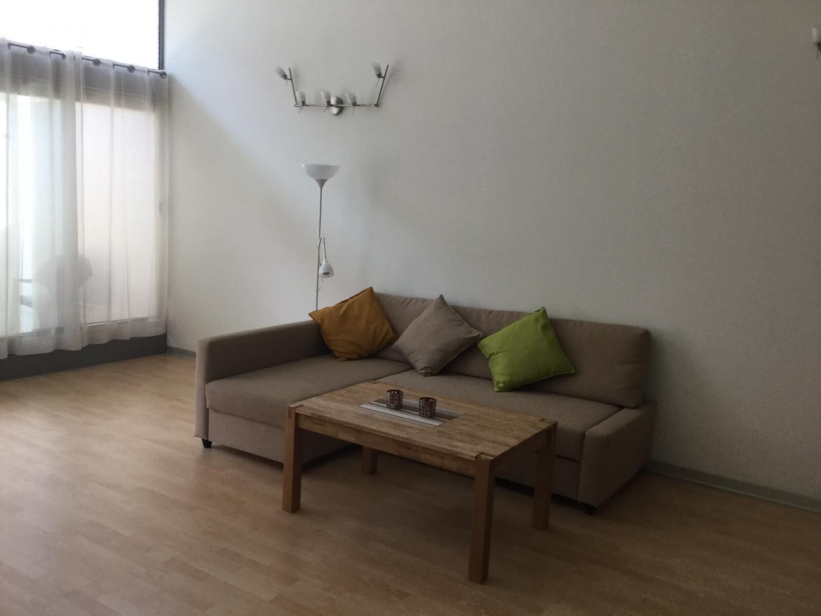 Un salon comprenant un canapé, une table basse, une lampe et un élément décoratif fixé au mur.