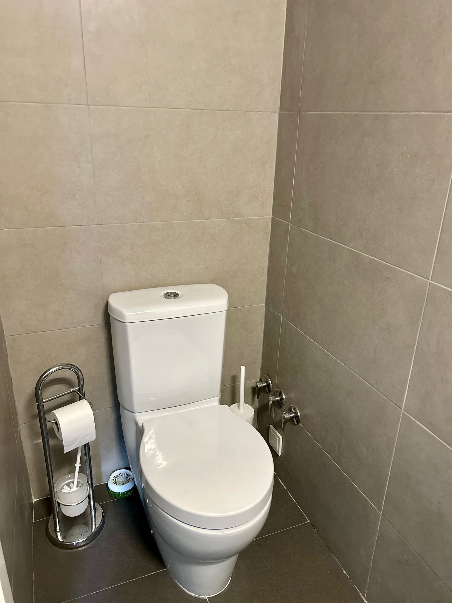 Un baño con un inodoro blanco, un dispensador de toallas de papel y un bidé.