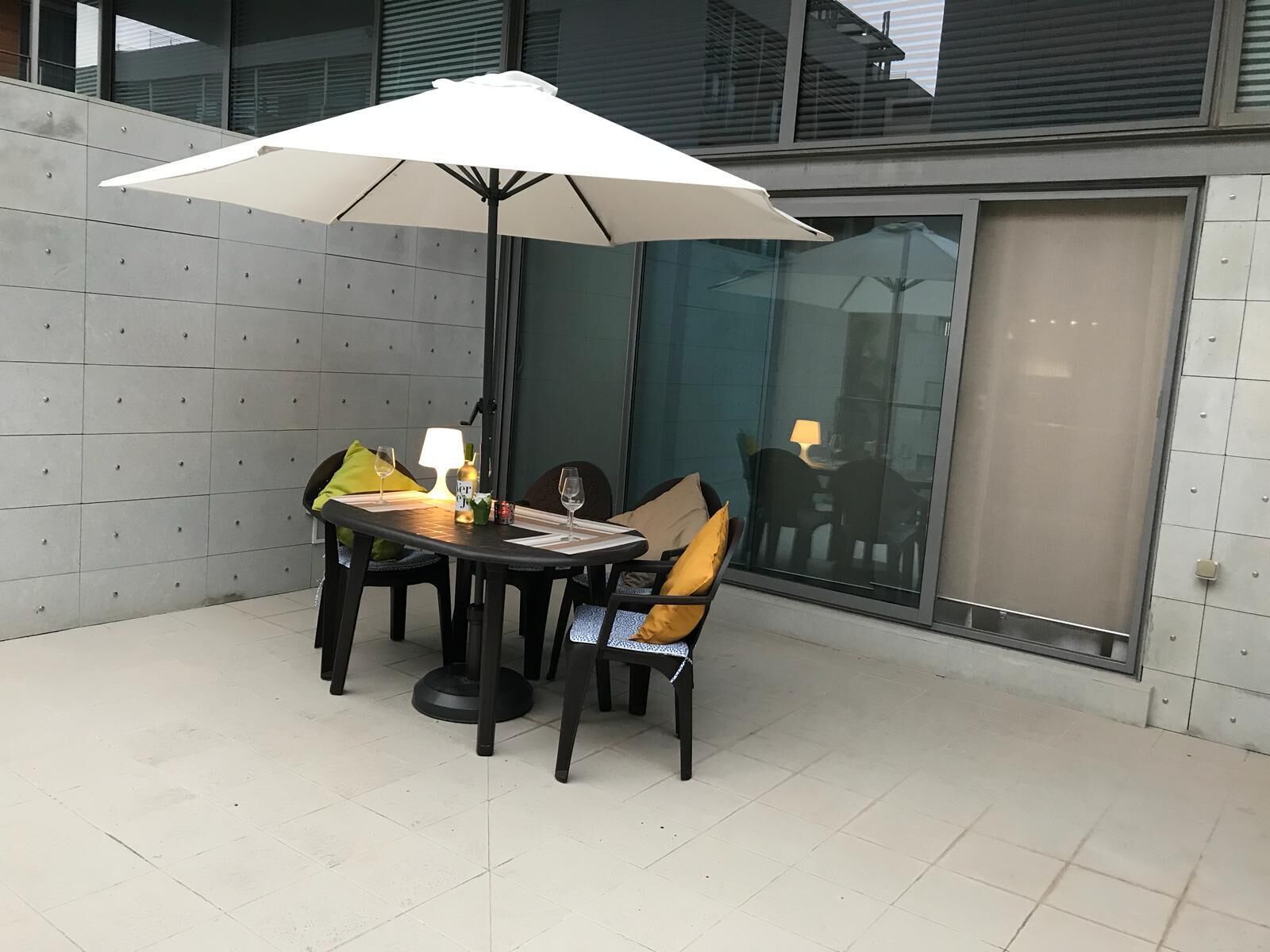 Ein Essbereich mit einem runden Tisch, vier Stühlen, einem weißen Sonnenschirm und einer Lampe.