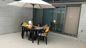 Ein Essbereich mit einem runden Tisch, vier Stühlen, einem weißen Sonnenschirm und einer Lampe.