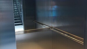Um elevador moderno com paredes metálicas e corrimão.