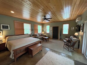 A bedroom with a bed, a desk, a chair, a sofa, and a ceiling fan.