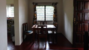 A dining area with a table and chairs, a window with curtains, and a door.