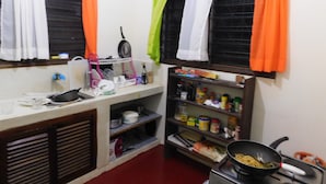 A compact kitchen with a sink, stove, and shelves stocked with kitchen items.