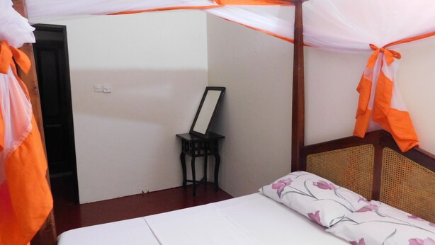 A room with a bed, a small table, and a door.