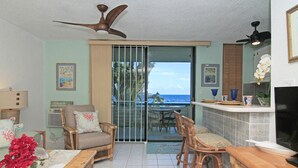 A living room with a view of the ocean, a ceiling fan, and a dining area with a TV. - Playa Linda - St. Thomas Oceanfront Studio Condo at Pool & Bolongo Beach, USVI (St. Thomas)