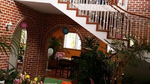 A multi-level brick interior with a staircase, indoor plants, and a dining area.