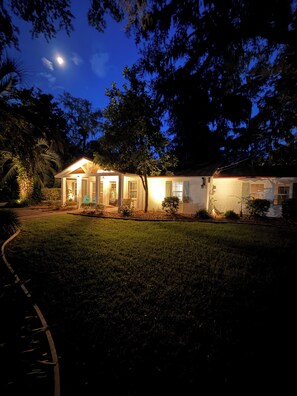 Uma casa com varanda, gramado e árvores.