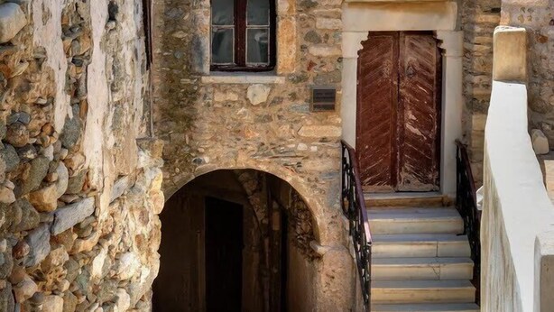 A narrow stone staircase leading to an arched doorway, flanked by stone walls and wooden doors. - My Home in Naxos Town With Sea View (Naxos)