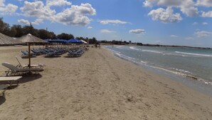 A beach with sun loungers and umbrellas, a sandy shore, and a clear sky. - My Home in Naxos Town With Sea View (Naxos)