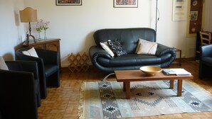 A living room with a black leather sofa, two armchairs, a wooden coffee table, and a patterned rug. - Air-conditioned & heated cottage in picturesque Pernes-les-Fontaines (Pernes-les-Fontaines)