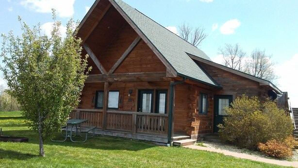 Eine Holzjagdhaus mit Veranda, Picknicktisch und Briefkasten.