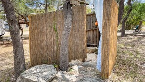 Un espace extérieur rustique agrémenté d’une clôture en bois, d’un tissu suspendu et d’un chemin en béton.