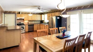 A spacious kitchen with wooden cabinets, a central island, and a dining area with a table and chairs. - Musician's Haven in Music City - 7 miles to downtown - off-street parking (Nashville)