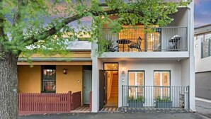 A two-story residential building with a balcony, a red fence, and a tree in the foreground. - Meko - Luxury Carlton House in Melbourne golden inner city (Carlton)