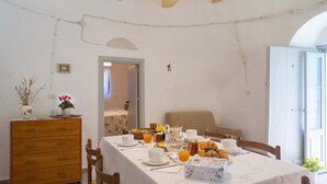 Ein Essbereich mit einem Tisch, der für das Frühstück gedeckt ist, inklusive Tellern, Tassen und einer Kanne Orangensaft.