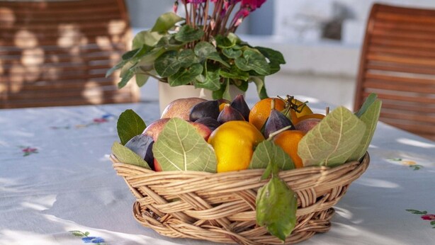 Ein Korankorb, gefüllt mit Früchten und Blumen, steht auf einem Tisch mit weißem Tuch.