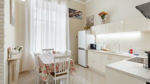 Uma cozinha moderna com armários brancos, geladeira, micro-ondas e cafeteira.