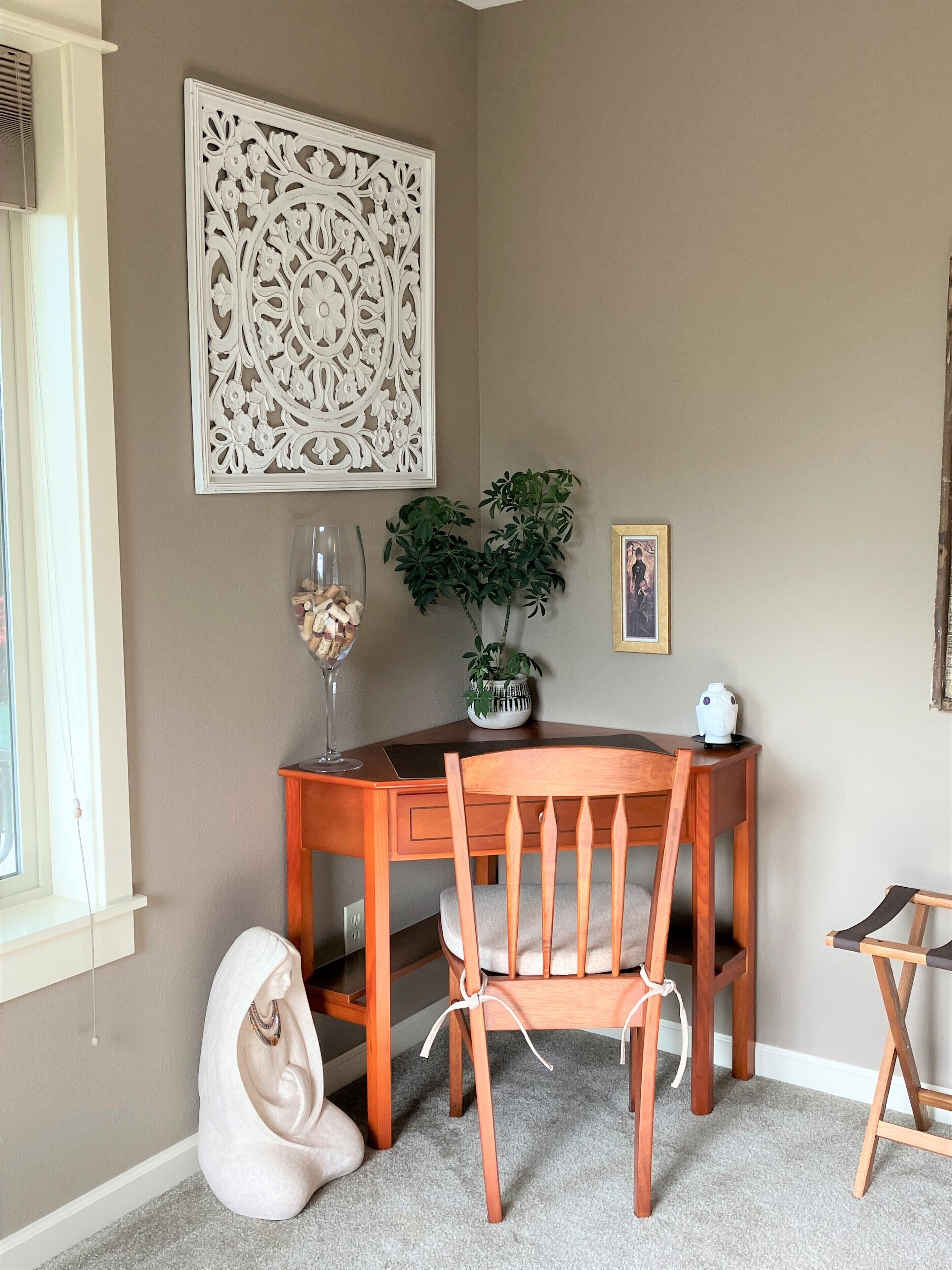 Un comedor con mesa y sillas de madera, un adorno en la pared, una planta en maceta y un cuadro enmarcado.