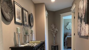 A hallway with a dark wooden console table, a vase with flowers, and framed pictures on the wall. - Spacious Single Party B&B – walking distance to downtown!  (Dundee)