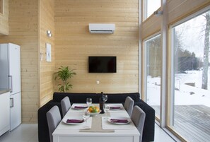 A modern kitchen with a built-in refrigerator, a dining area with a table set for four, and a large window offering a view of a snowy landscape.