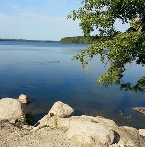 A calm lake with clear water, surrounded by large rocks and trees.