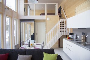 En moderne lejlighed i loftstil med spiseplads, køkken og trappe op til en etage.