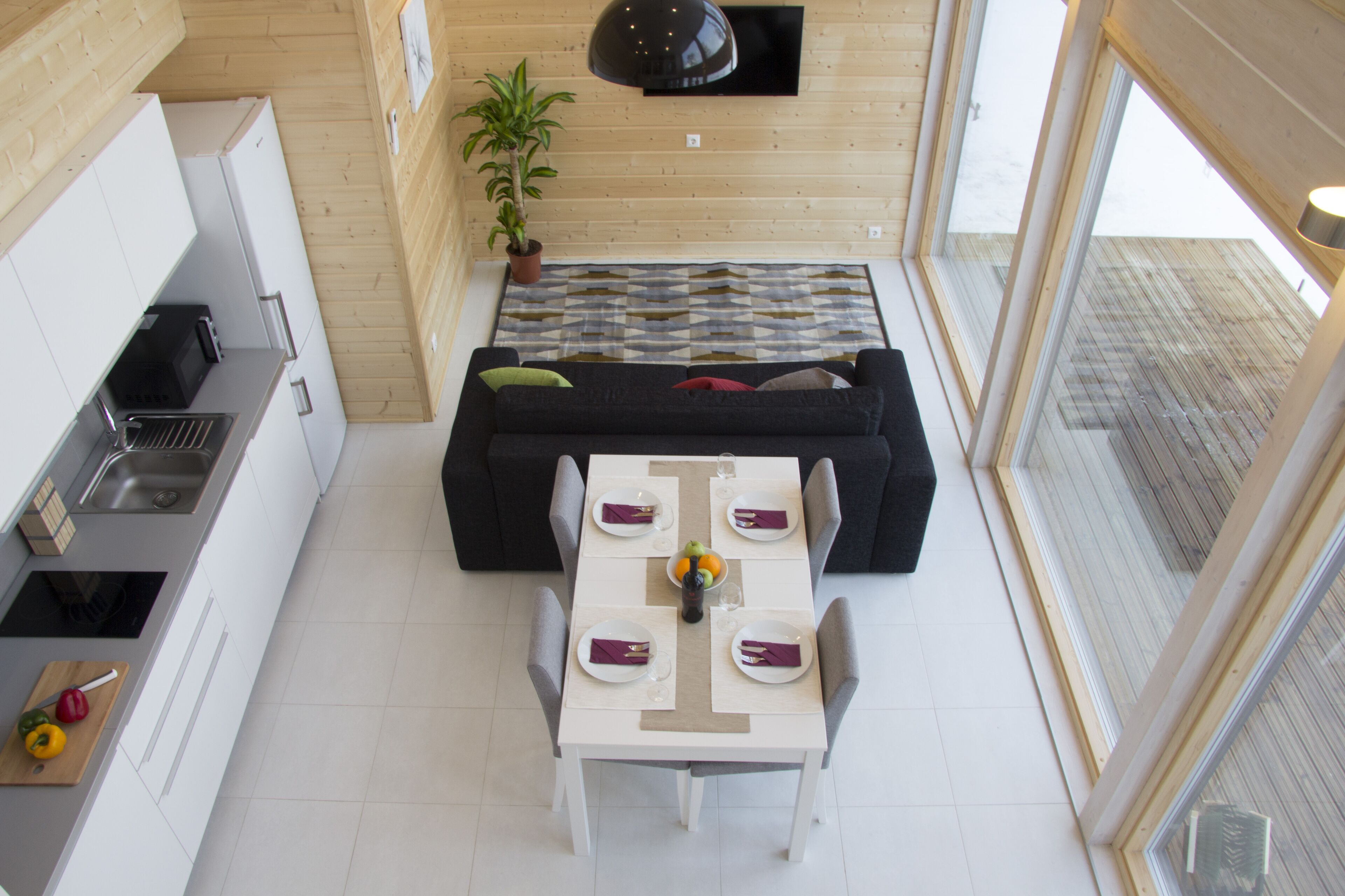 Cozinha compacta com área de refeições, um sofá preto e uma mesa de jantar para quatro pessoas.