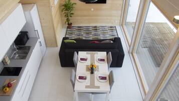 Cozinha compacta com área de refeições, um sofá preto e uma mesa de jantar para quatro pessoas.