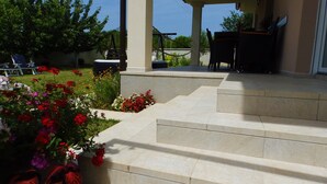A covered outdoor area with steps leading to a patio, surrounded by a garden with various flowers. - Entire house just for you! (Pula)
