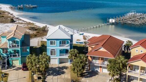 Une propriété située sur la côte, avec vue sur la plage, un quai et une maison à deux étages dotée d’un balcon.