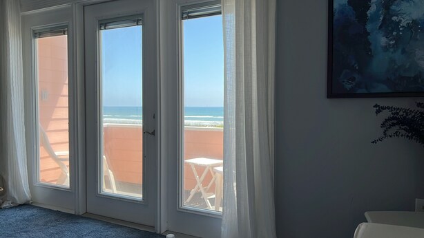 Una habitación con vista al mar a través de un ventanal corredizo.
