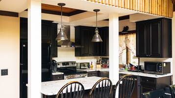 A kitchen with black cabinets, a white countertop, and a central island with chairs.