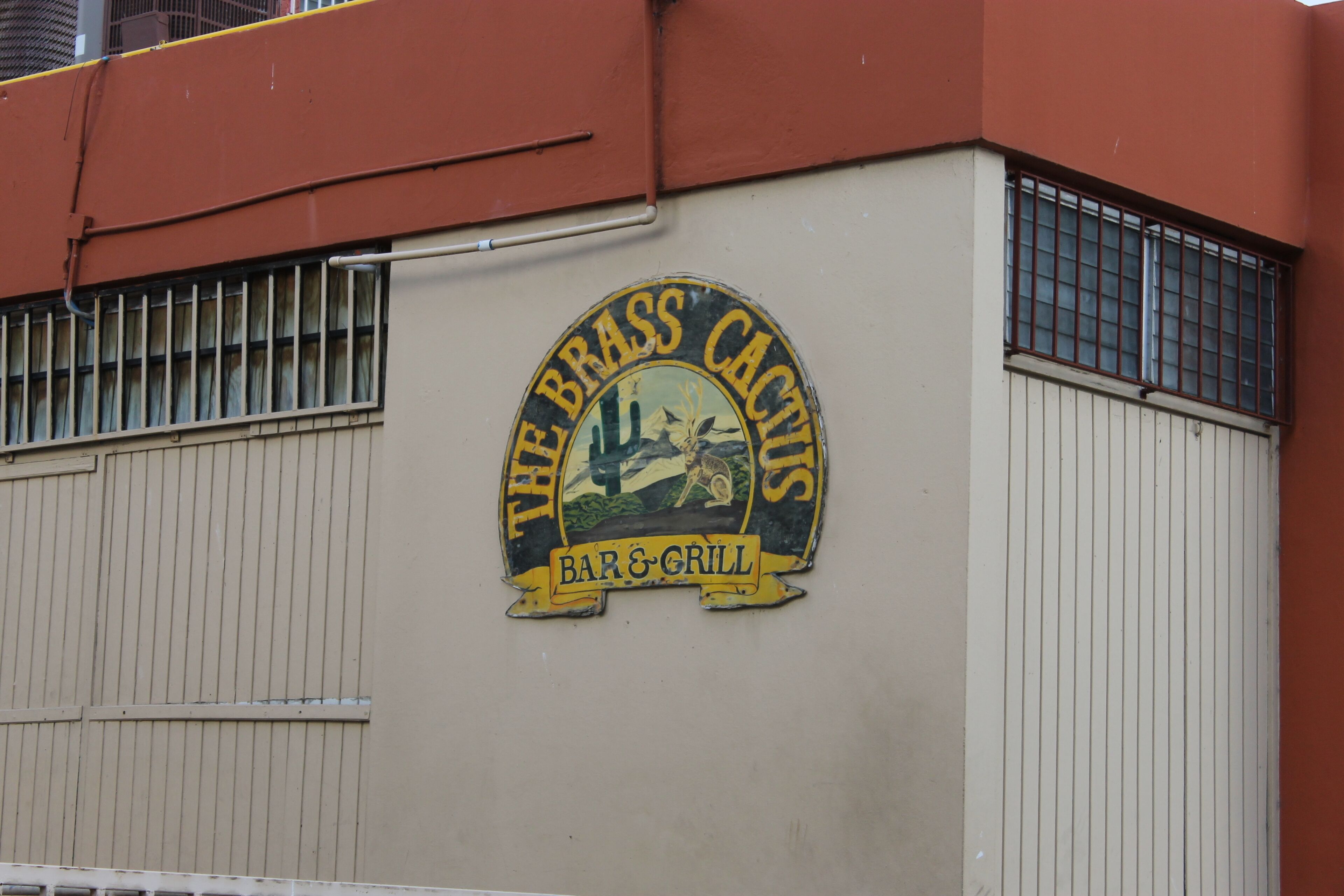 Um edifício com uma placa que diz 'The Brass Cactus Bar & Grill'.